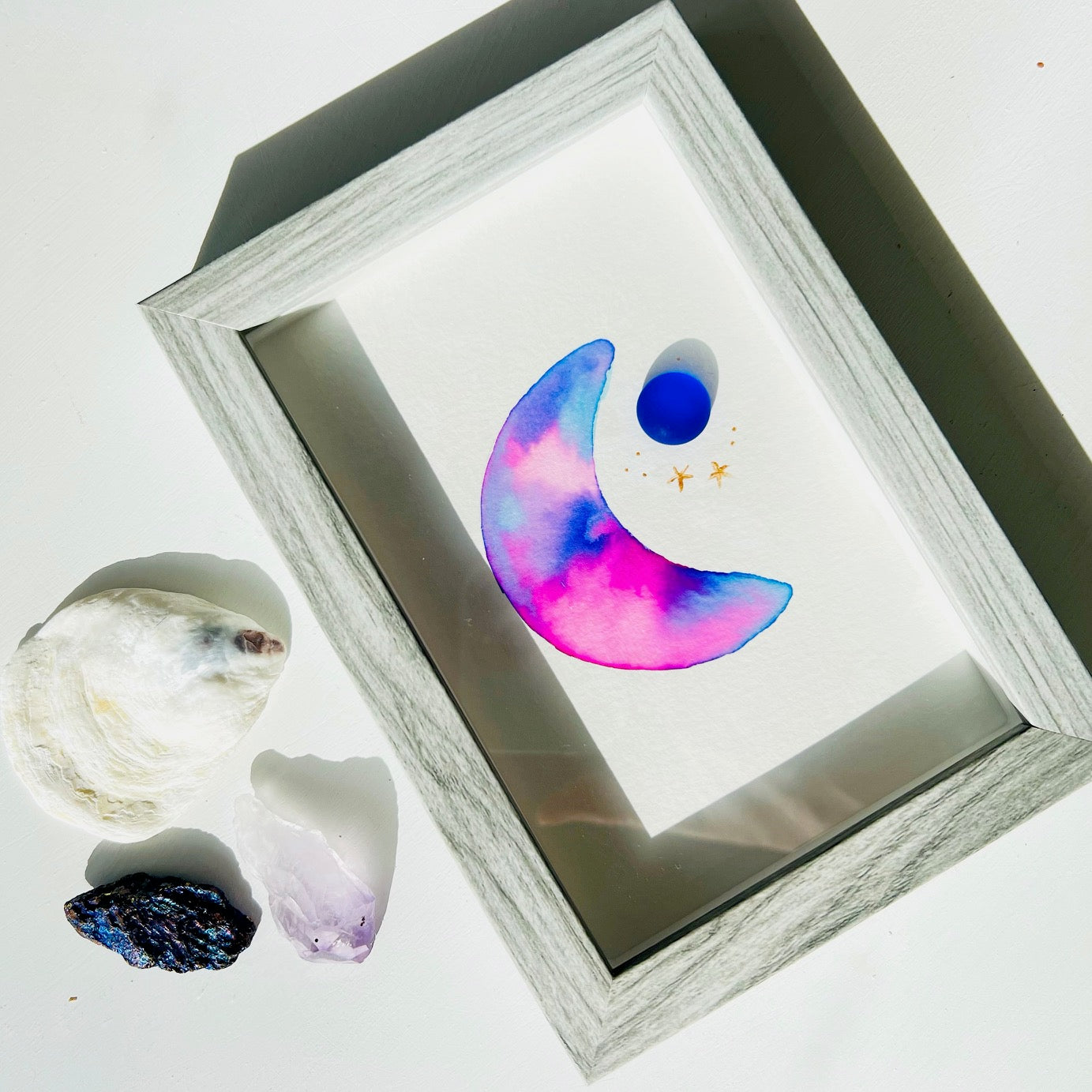 Original sea glass artwork featuring a beautiful watercolor crescent moon and a frosty piece of cobalt blue glass. Artwork is displayed in a 4"x6" shadowbox frame.