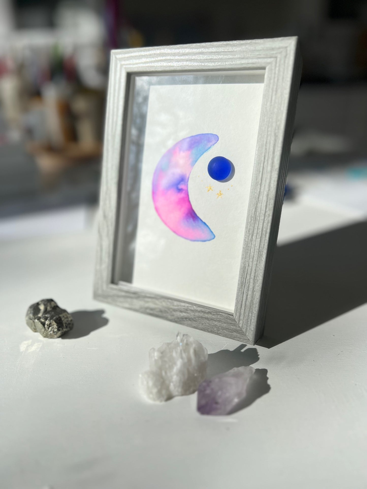 Original sea glass artwork featuring a beautiful watercolor crescent moon and a frosty piece of cobalt blue glass. Artwork is displayed in a 4"x6" shadowbox frame.