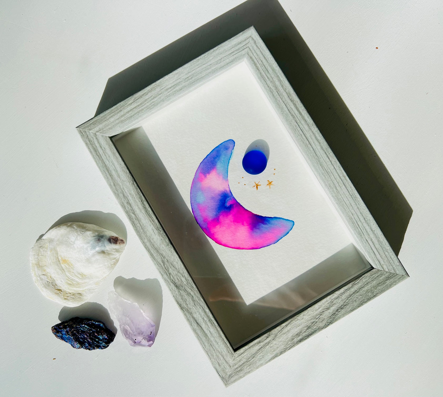 Original sea glass artwork featuring a beautiful watercolor crescent moon and a frosty piece of cobalt blue glass. Artwork is displayed in a 4"x6" shadowbox frame.