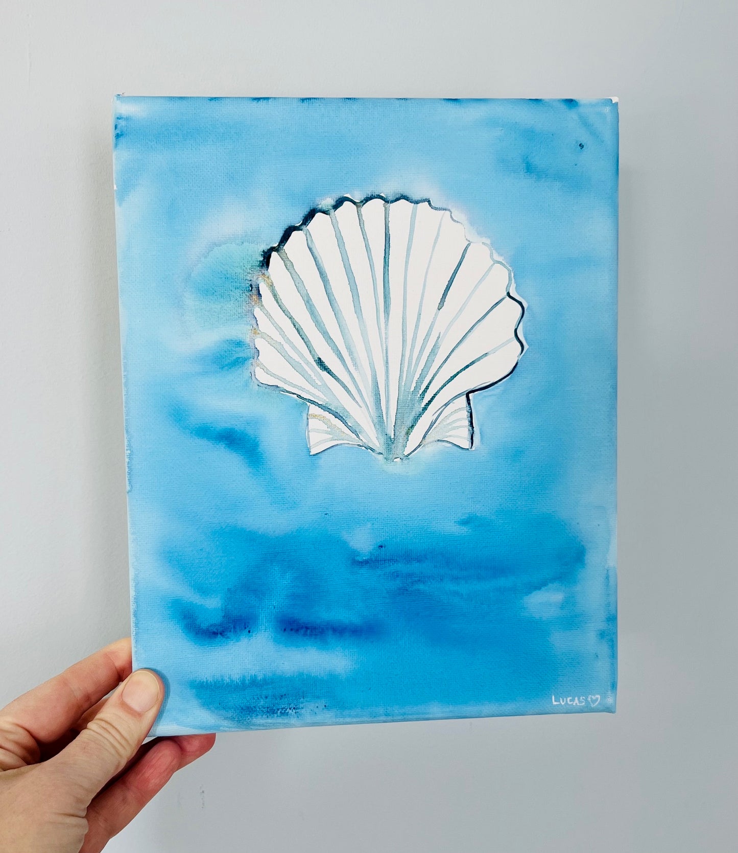 Watercolor seashell painted on canvas with layered ocean blues, coastal art by Ashley Lucas