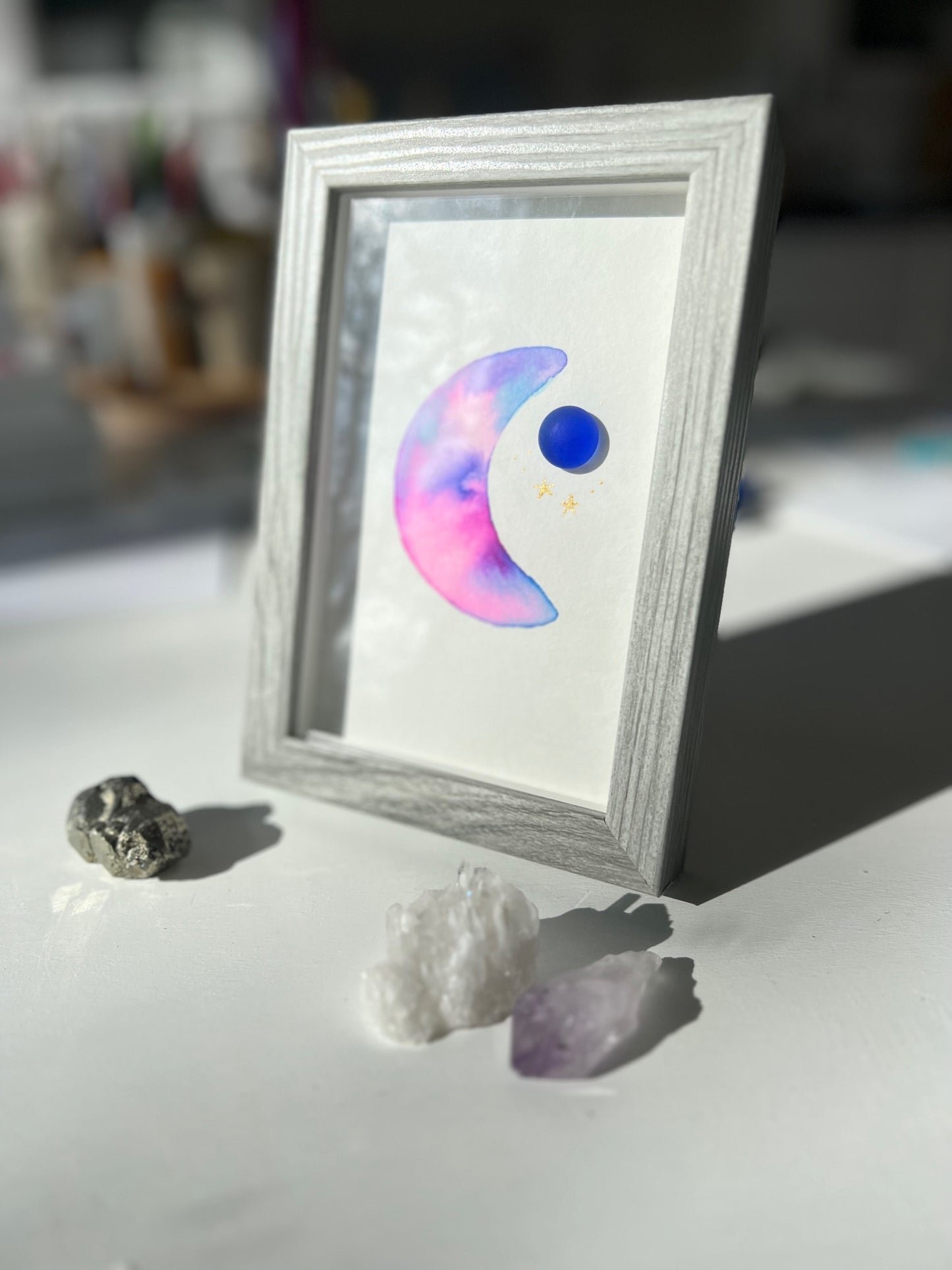 Original sea glass artwork featuring a beautiful watercolor crescent moon and a frosty piece of cobalt blue glass.   Artwork is displayed in a 4"x6" shadowbox frame. 